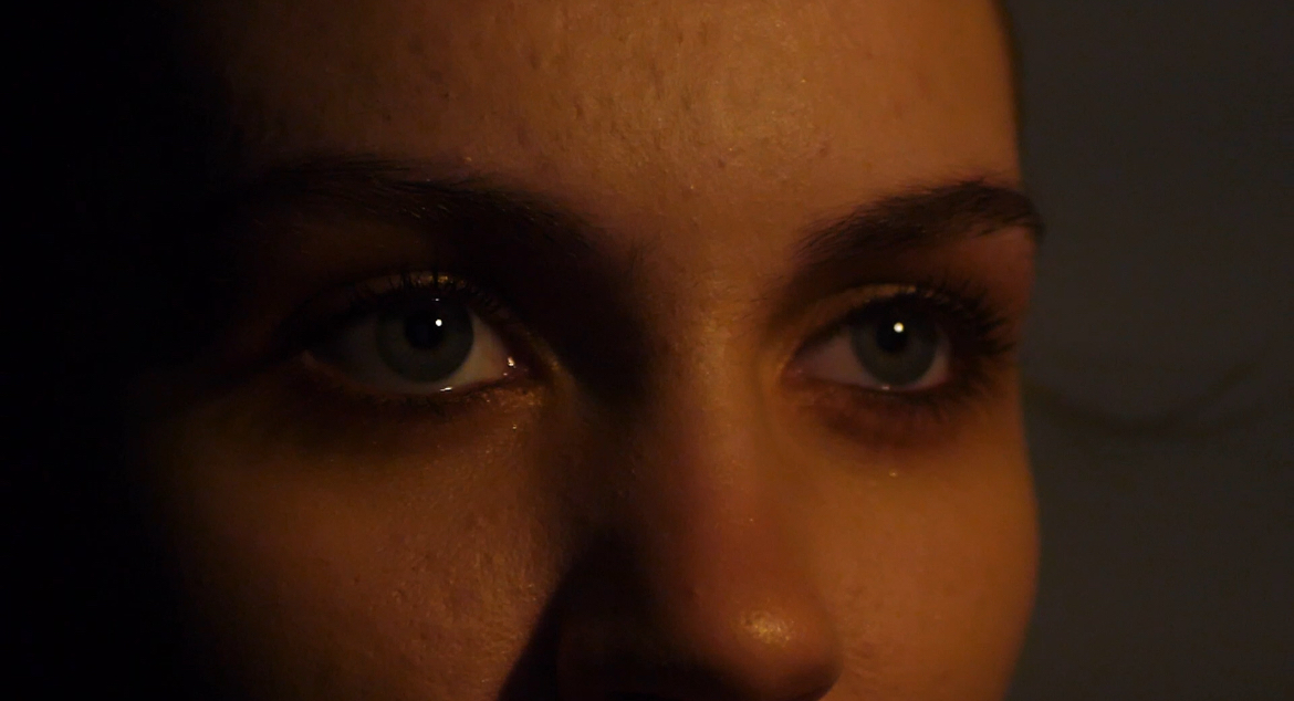Extreme close-up of a young woman's eyes lit by warm tungsten light